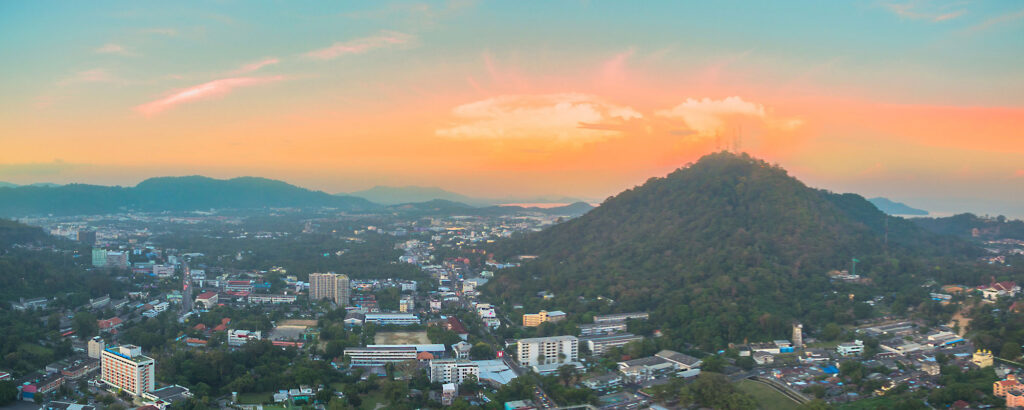View of Phuket and surrounding hills at sunset, showing urban development and natural landscape