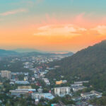 View of Phuket and surrounding hills at sunset, showing urban development and natural landscape