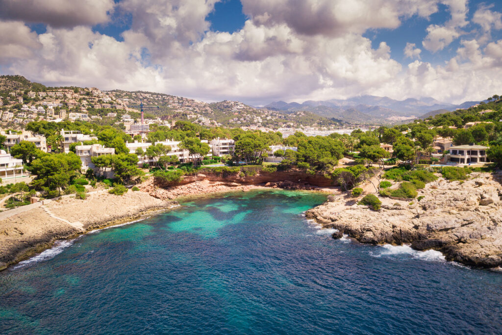 Aerial view of villas on the cliffs above Cala Marmassen Bay in Andratx, Mallorca, with turquoise water and coastal landscape