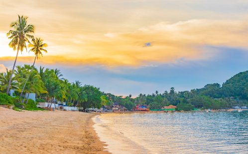 Koh Samui beachfront at sunset, showing palm-lined shoreline and calm sea